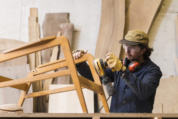 male-carpenter-sanding-wood-with-orbital-sander-workshop